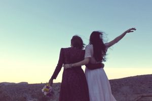 Zwei Frauen umarmen sich in Hochzeitskleidern